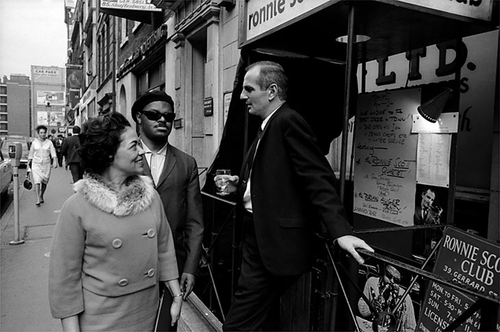 Ronnie Scott with Roland & Edith Kirk outside 39, Gerrard Street. (1963)